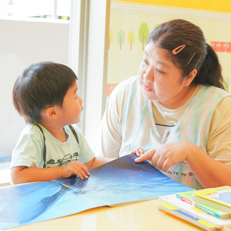 先生と男の子が目を合わせながら絵本を読む様子