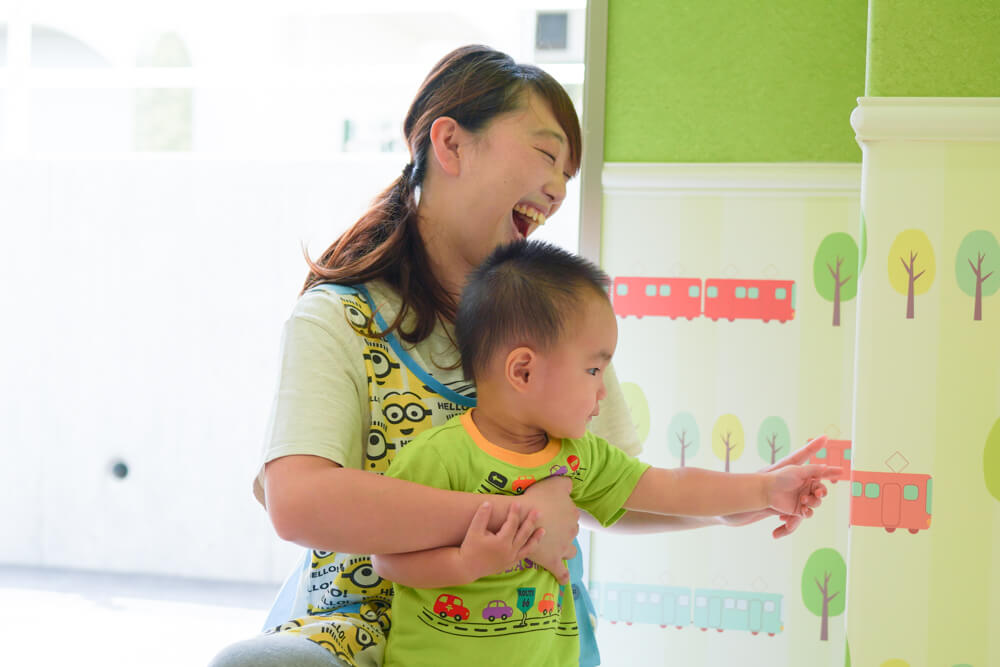 男の子と先生が電車柄の壁紙を指差して笑っている様子